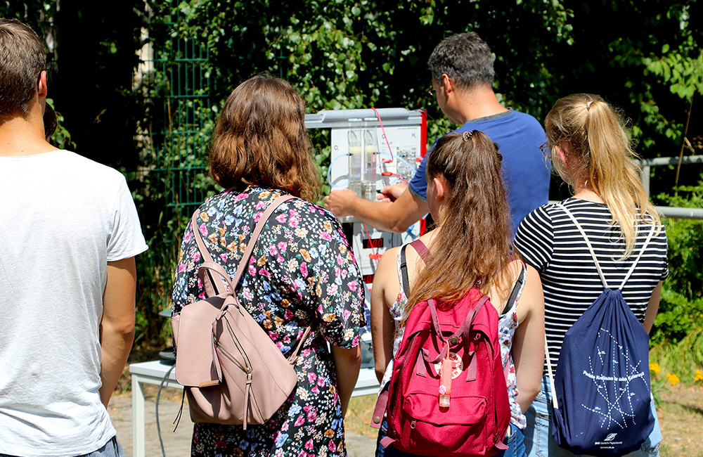 Gruppenaufnahme von Schülern im Freien die sich eine Infotafel ansehen