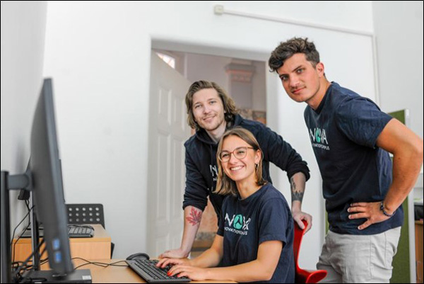 3 Personen des Nova-Gründerteams sitzen vor einem PC und blicken in die Kamera