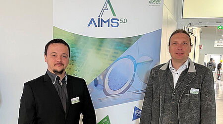 Arnold Lange und Prof. Mark Vehse vor einem Werbeaufsteller des Aims-Projektes