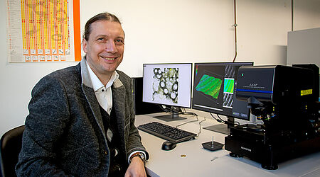 Prof. Mark Vehse sitzt am PC mit Laser-Scanning-Mikroskop