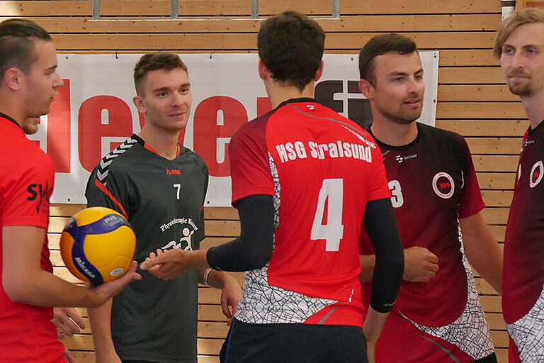 5 männliche Studierende der HOST-Volleyballer in roten Trikots im Gespräch