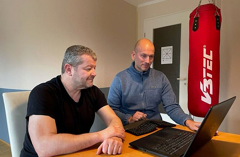 David Joecks und Torsten Rollberg schauen auf einen Laptop