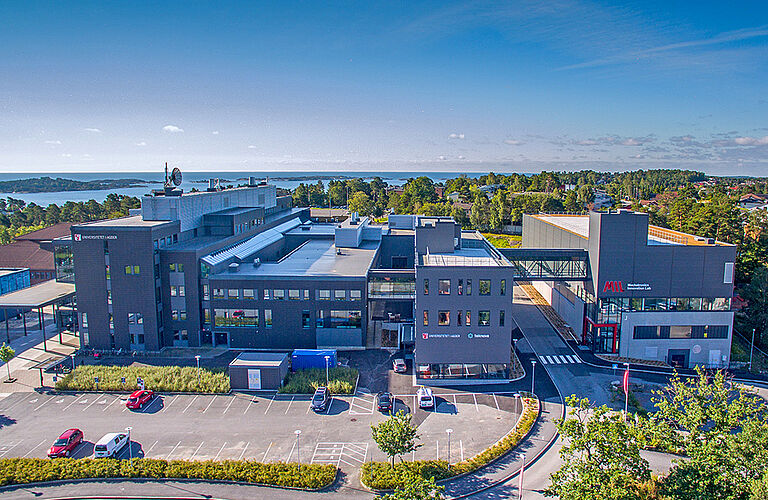 Luftaufnahme des Campusgelände mit Gebäuden und Parkplätzen der University of Agder in Grimstad