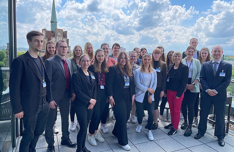 Gruppenfoto von 2 Dutzend Studierenden in Anzügen und Blaisern mit Lehrenden der Fakultät für Wirtschaft auf einer Dachterrasse