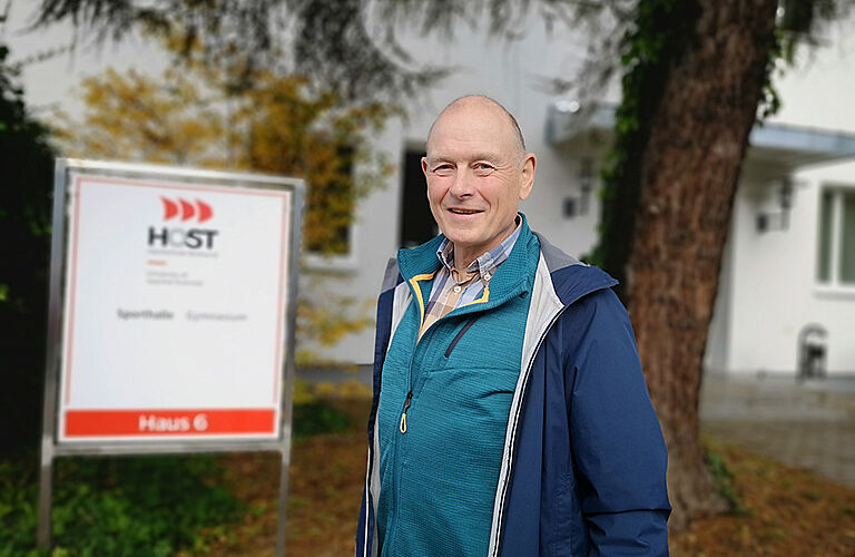 Prof. Wolfgang Schikorr in blauer Sportjacke vor der Turnhalle der HOST