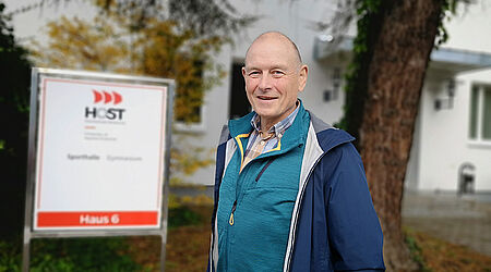 Prof. Wolfgang Schikorr in blauer Sportjacke vor der Turnhalle der HOST