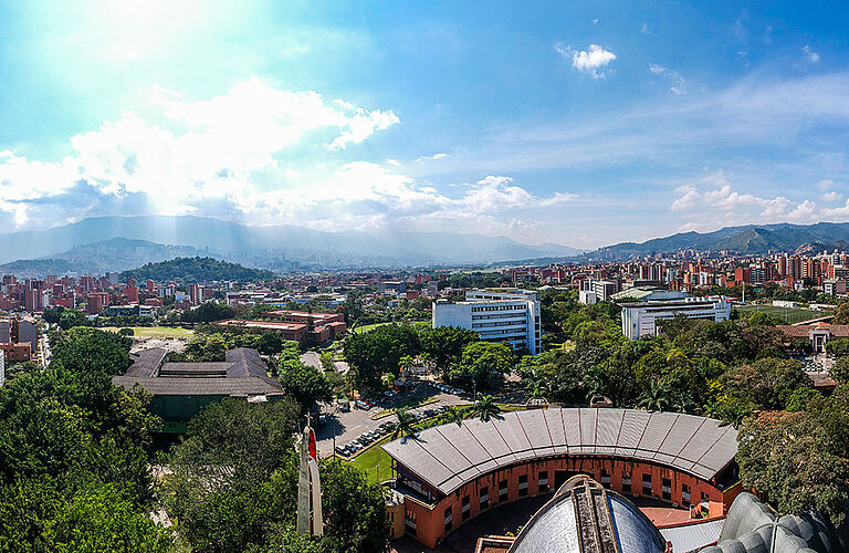 Luftaufnahme des Campus Universidad Pontificia Bolivariana bei Sonnenschein und mit Bergkulisse im Hintergrund