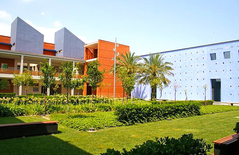 Grünanlage mit Palmen und blauen Gebäuden im Hintergrunde auf dem Campus Gandia der Universitat Politècnica de València