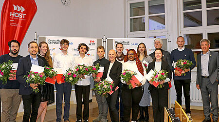 Ein Gruppenfoto von Stipendiat*innen mit Blumen und Fördermittelgeber*innen zur Verleihung des Deutschlandstipendiums 2023 an der HOST