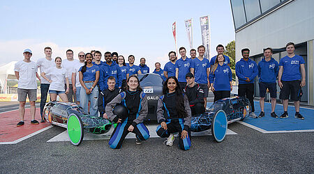 ca. 2 Dutzend Menschen vom ThaiGer-H2-Racing-Team in blauen Hoodies und dem Schüler-Team Greendrive mit 3 Rennwagen des Shell-Eco-Marathon