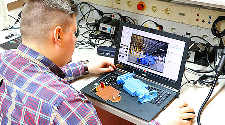 Mann im E-Technik-Labor, welcher am Laptop ein CAD-Model bearbeitet