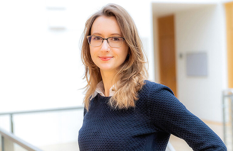 seitliches Portraitfoto von Sarah Gnoth mit Brille und blauem Pullover