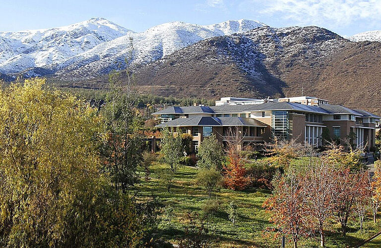 Gebäude der Universidad de los Andes mit grünen Bäumen und schneebedeckten Bergen im Hintergrund