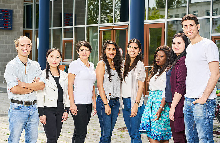 8 internationale Studierende bei Sonnenschein vor dem Maschienenbau-Gebäude der HOST