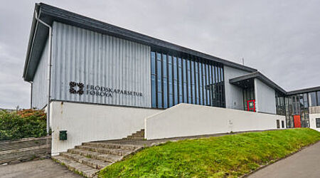 Aufnahme eines grau-blauen gebäudes mit gläsernem EIngangsbereich der University of the Faroe Islands