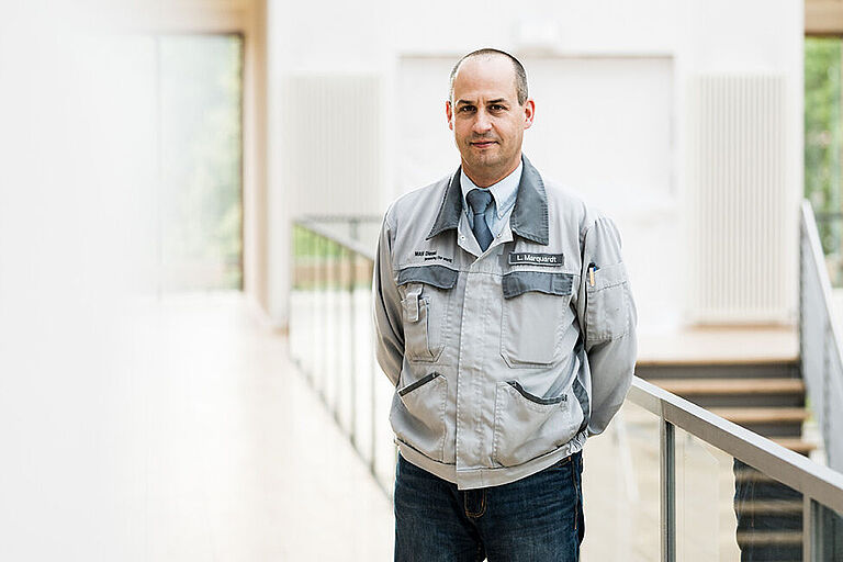 Prof. Leander Marquardt mit Werkstattjacke auf einem Flur