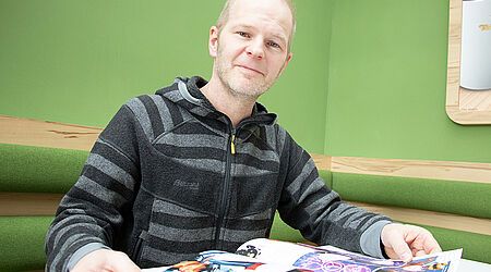 Prof. Gero Szepannek mit dem KI-Comic in der Cafeteria der HOST