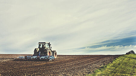 Traktor von hinten, der ein Feld pflügt