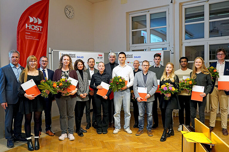 Ein Gruppenfoto mit gut 20 Personen, die teilweise Blumen und Urkunden halten.