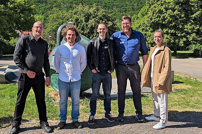 Fünf lächelnde Menschen - Martin Morgenstern, Torsten Wieck, Waldemar Adam, Jan Schmidt, Maria Freyer - stehen im Grünen bei strahlendem Sonnenschein