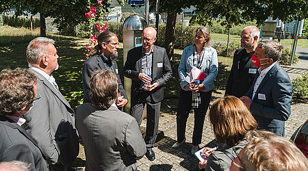 Personengruppe im Freien bei Sonnenschein die eine Pressekonferenz abhält