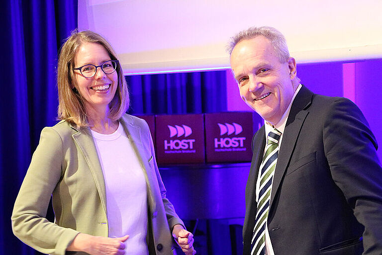 Anne Brorhilker und Prof. Thomas Eisgruber vor einem lilafarbenen Hintergrund beim Studium Generale der HOST