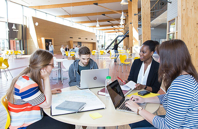 4 internationale Studierende mit Laptops in der Cateteria der Linnaeus University