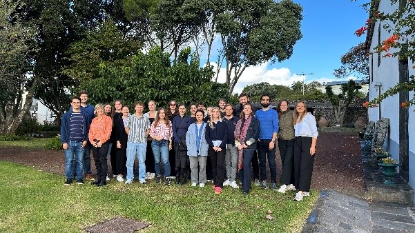 eine Gruppe von Menschen neben einem Gebäude im Grünen zum Gruppenfoto aufgestellt